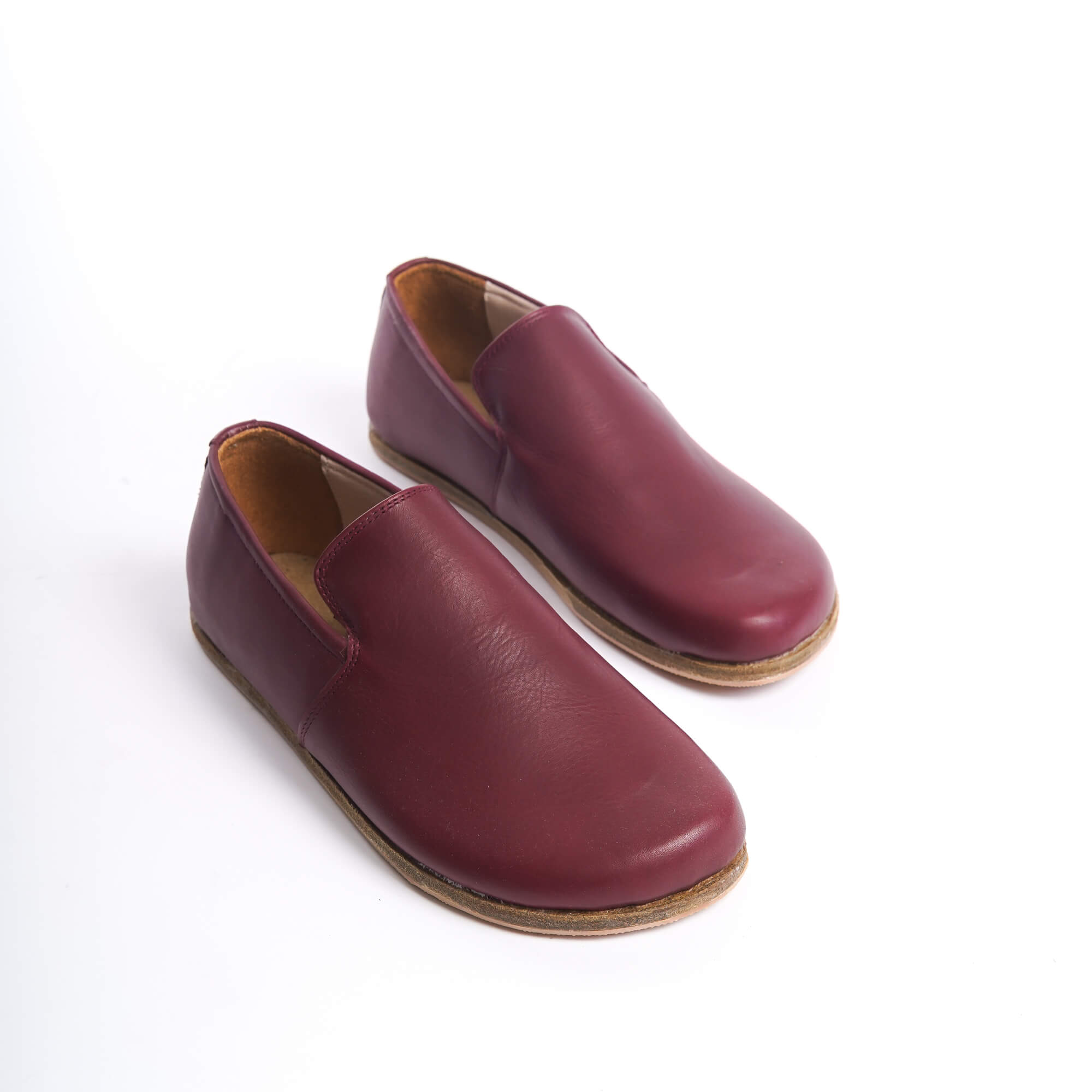 Pair of maroon genuine leather barefoot loafers showcasing a sleek and minimalist design with zero-drop soles. These shoes provide a natural fit and enhance foot health with their flexible, lightweight construction.