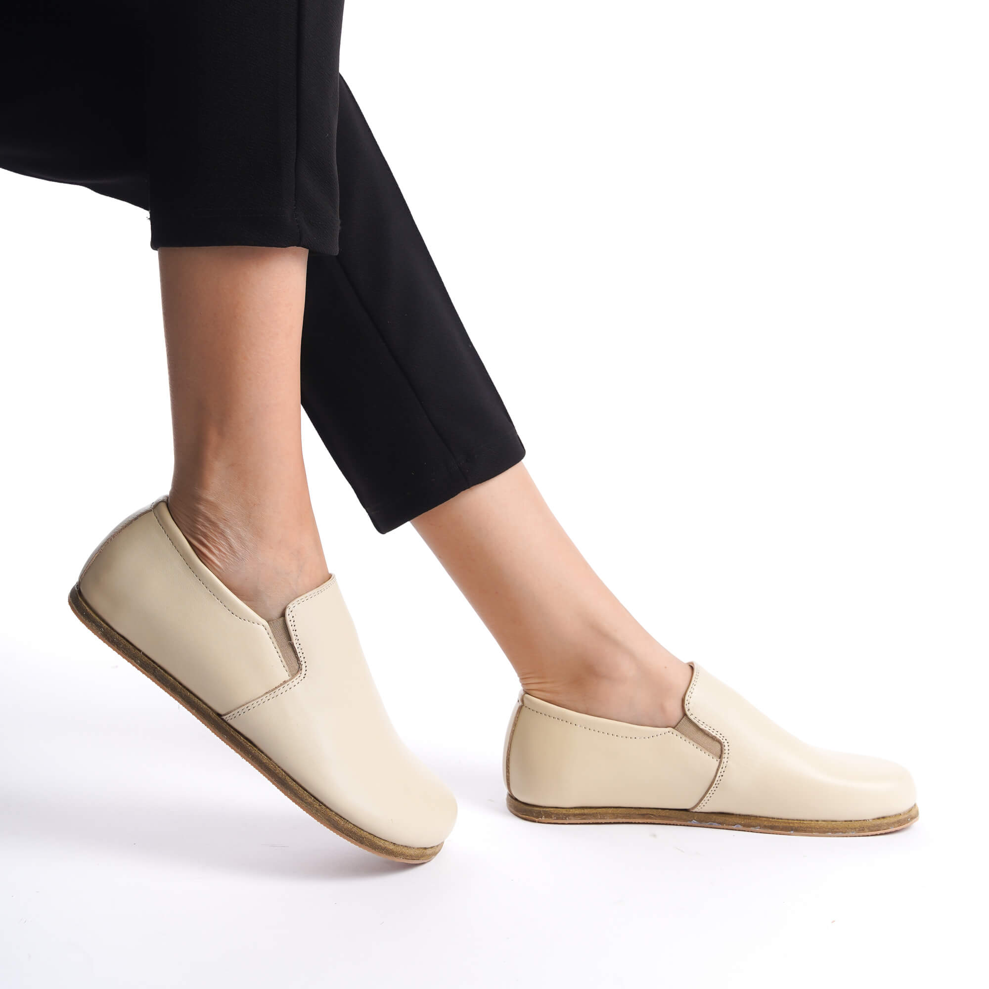 Close-up of a person wearing beige genuine leather barefoot loafers with a minimalist design and zero-drop soles.
