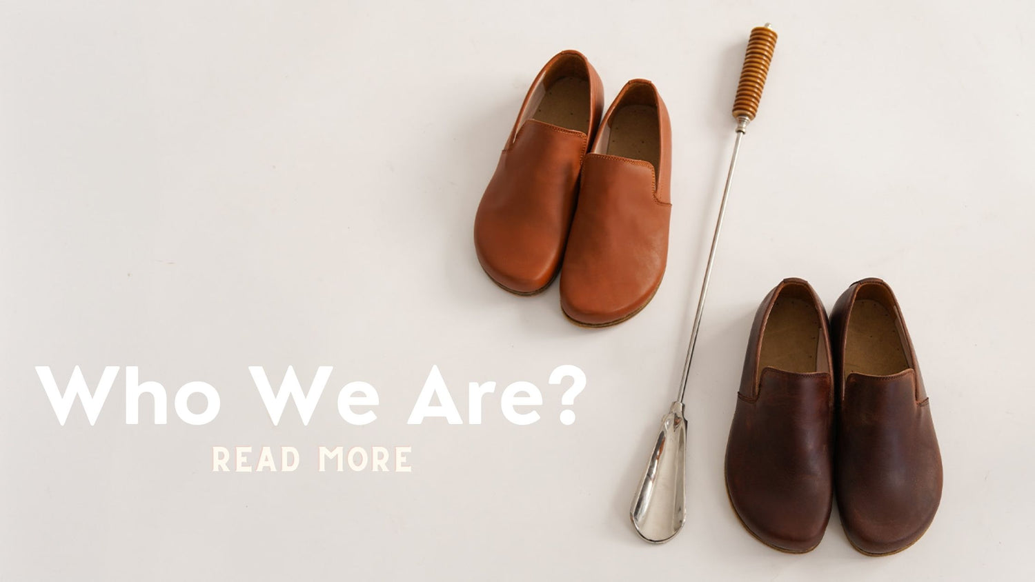 "Who Are We?" on a white background Two brown leather slip-on shoes next to a retro shoe horn that says: 'Read More' text that invites brand discovery.