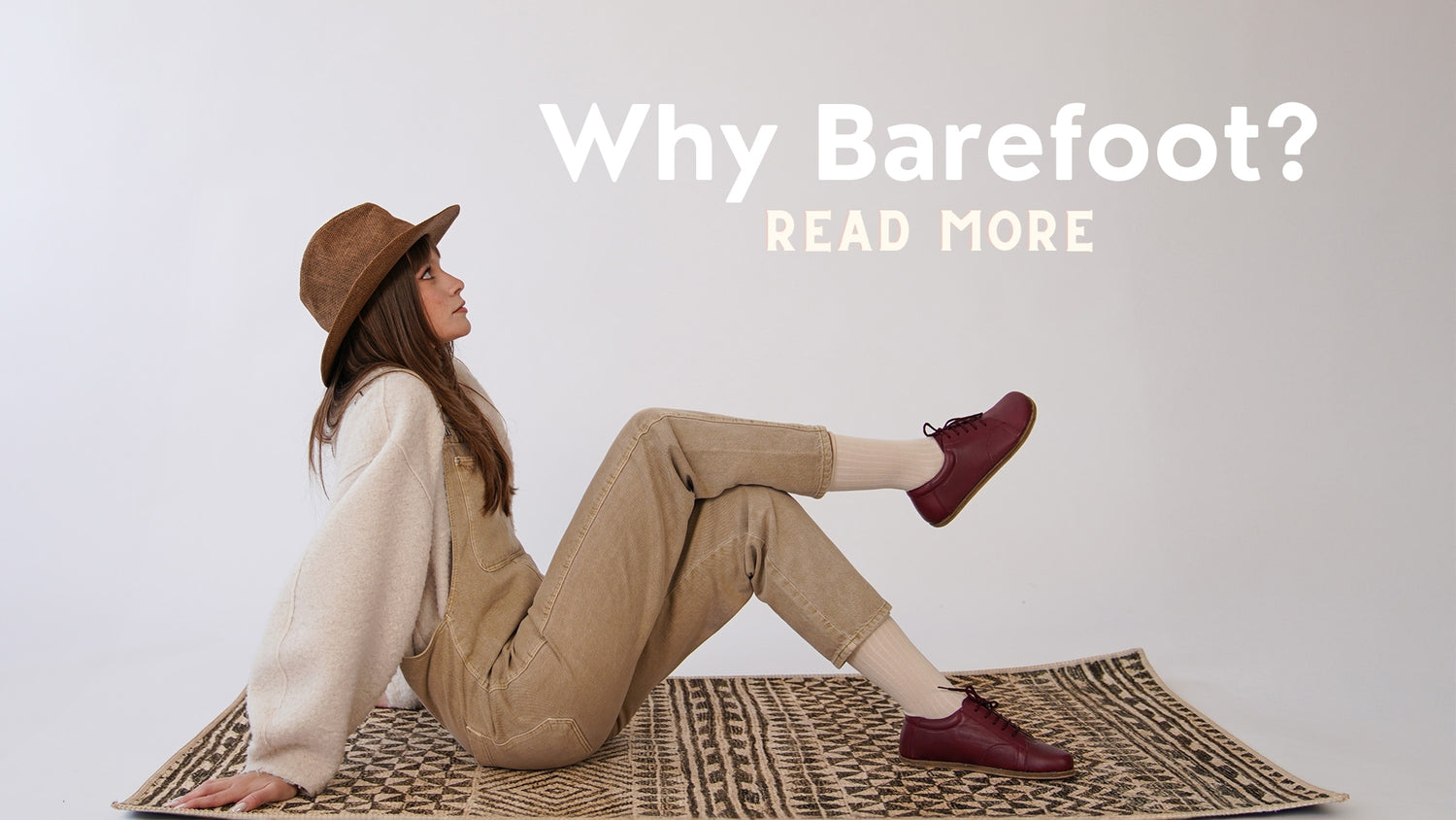 Woman in burgundy lace-up shoes and casual attire on a rug, with 'Why Barefoot? Read More' text in minimalist white font.