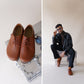 Model sitting with Locris Leather Barefoot Men's Oxfords in tan brown, paired with black pants, showcasing their stylish versatility.