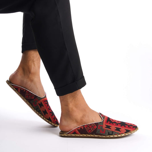 Person lifting foot wearing traditional Turkish slippers in red and black.