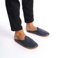 Person standing in navy blue leather slippers with natural leather soles.