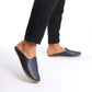 Person walking in simple navy blue leather slippers.