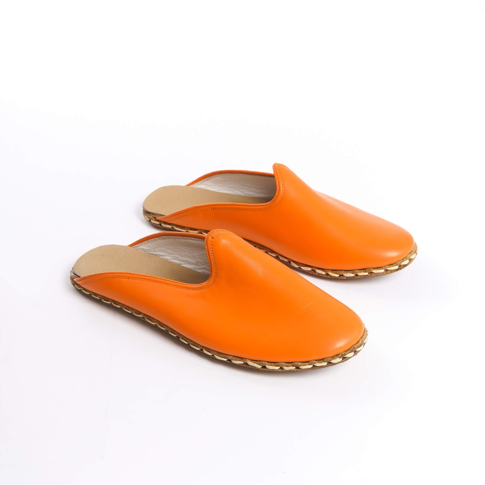 Close-up of orange leather slippers with natural leather soles.