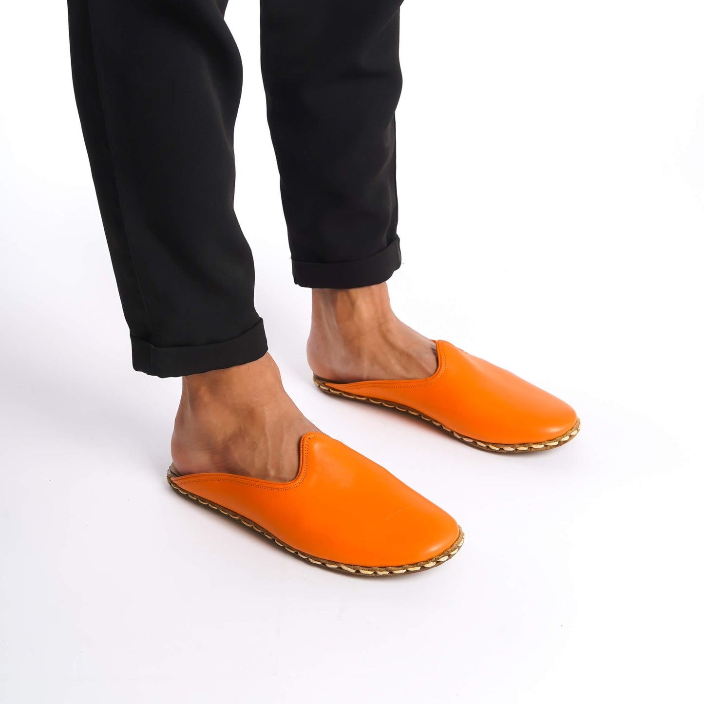 Person standing in orange leather slippers with genuine leather zero-drop soles.