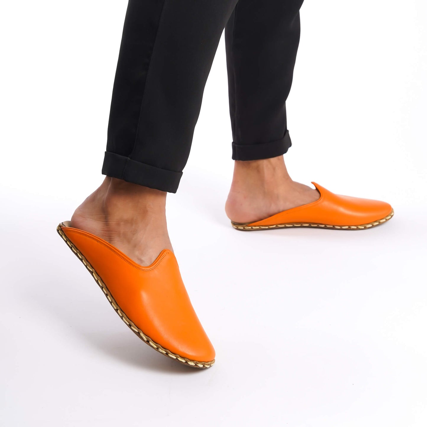 Person walking in vibrant orange leather slippers.