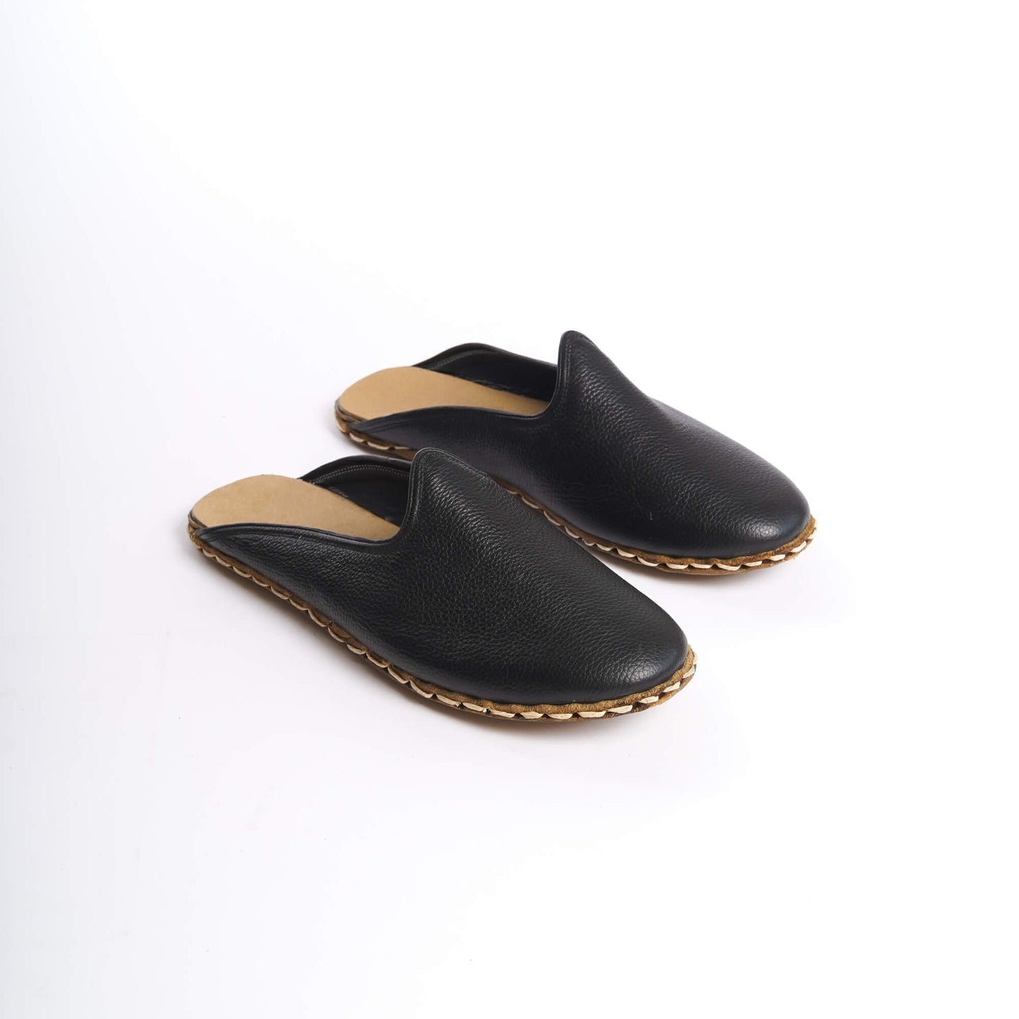 Close-up of black leather slippers featuring natural leather soles, zero drop design, and edge stitching.