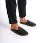 Person standing in black leather slippers with natural leather soles, zero drop design, and edge stitching.