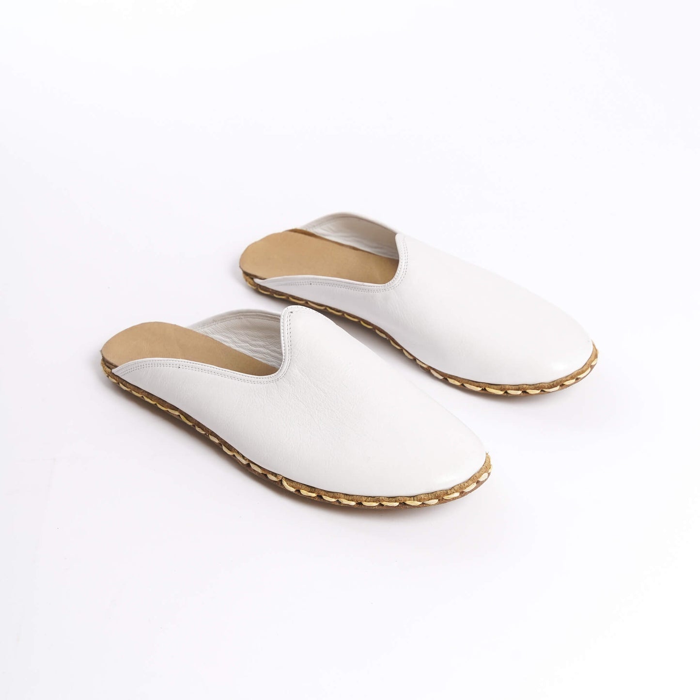 Close-up of white leather slippers featuring natural leather soles, zero drop design, and edge stitching.