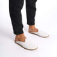 Person standing in white leather slippers with natural leather soles, zero drop design, and edge stitching.