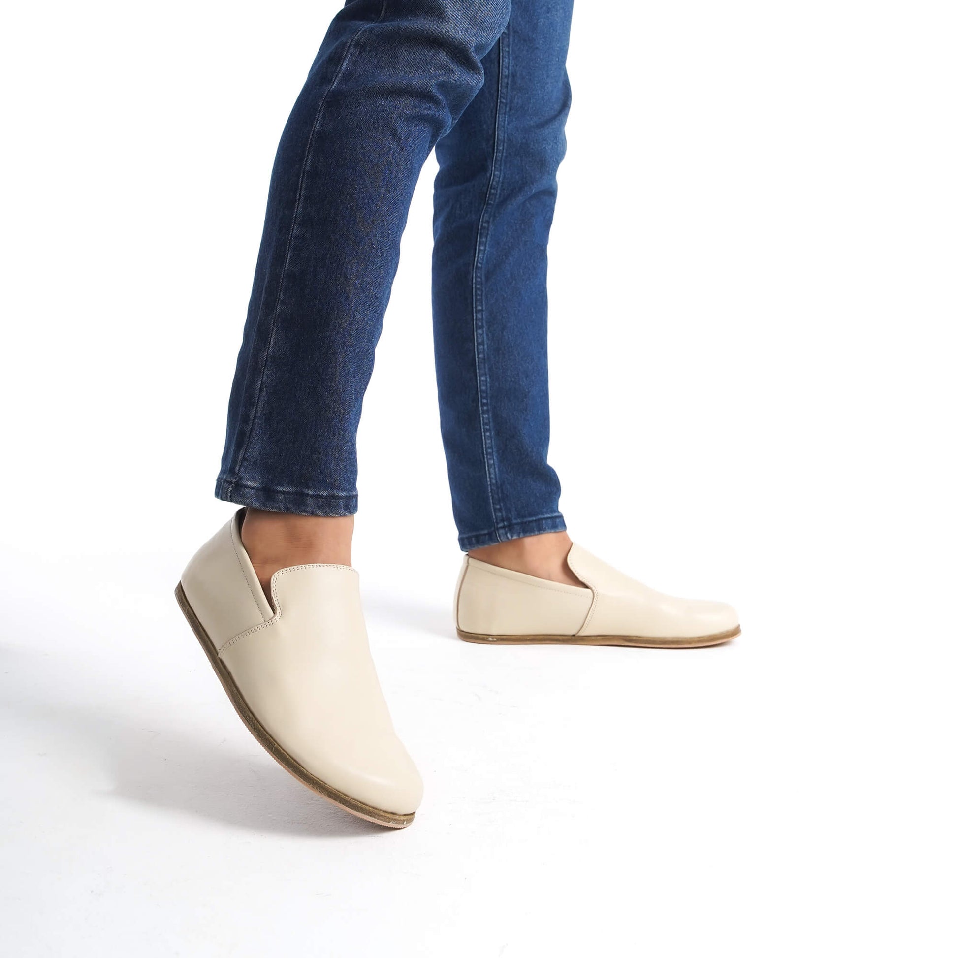 Men's feet wearing Aeolia Leather Barefoot Men Loafers in beige with blue jeans - shop at pelanir.com.