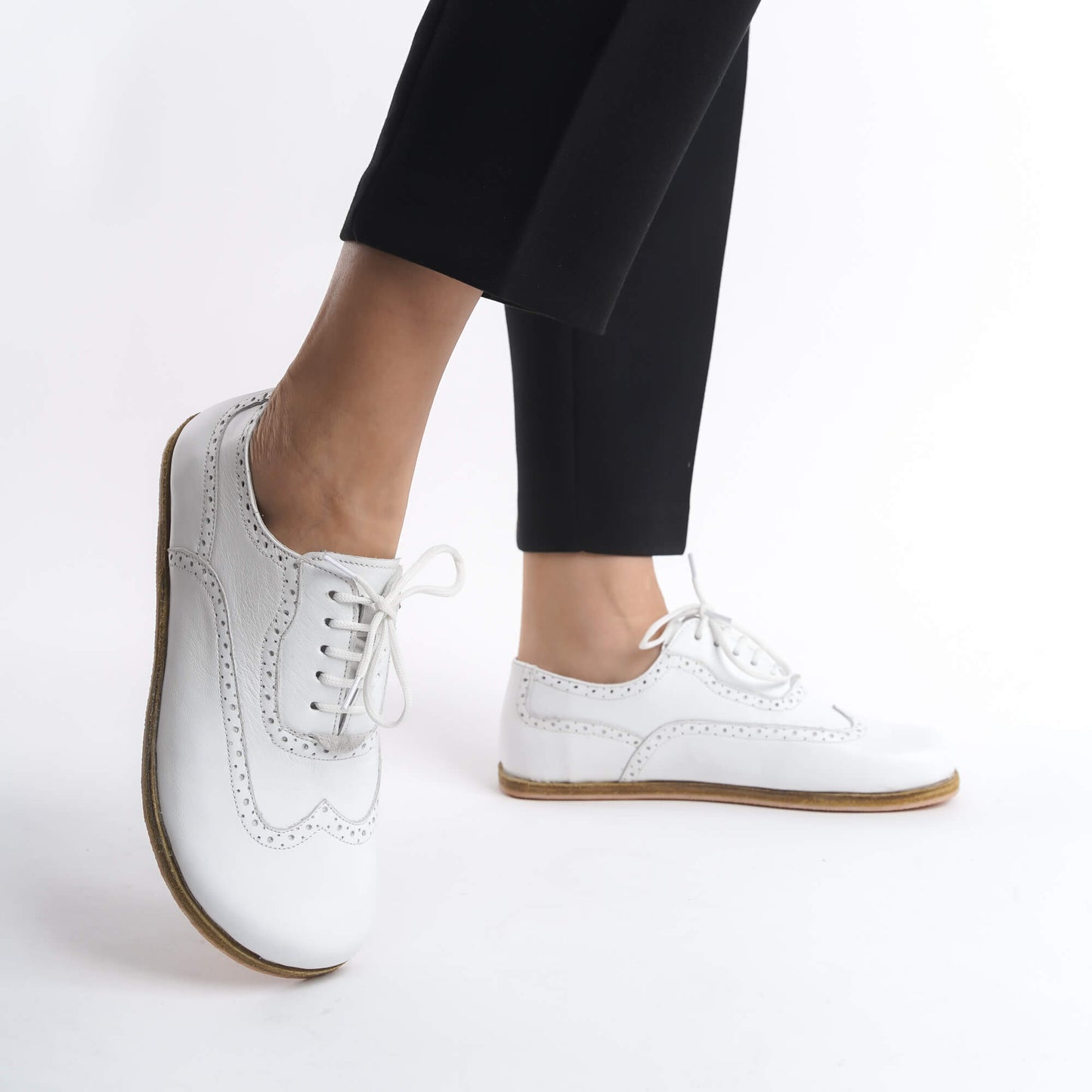 Model showcasing Doris Leather Barefoot Women's Oxfords in White with detailed stitching, paired with black pants