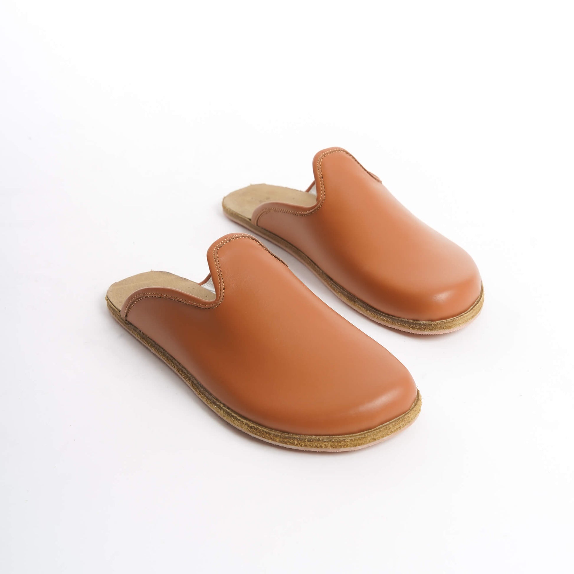 Classic tan leather slip-on shoes with a cushioned cork sole, designed for women who love versatile footwear. These eco-friendly and durable shoes are perfect for the U.S. market’s diverse styles.