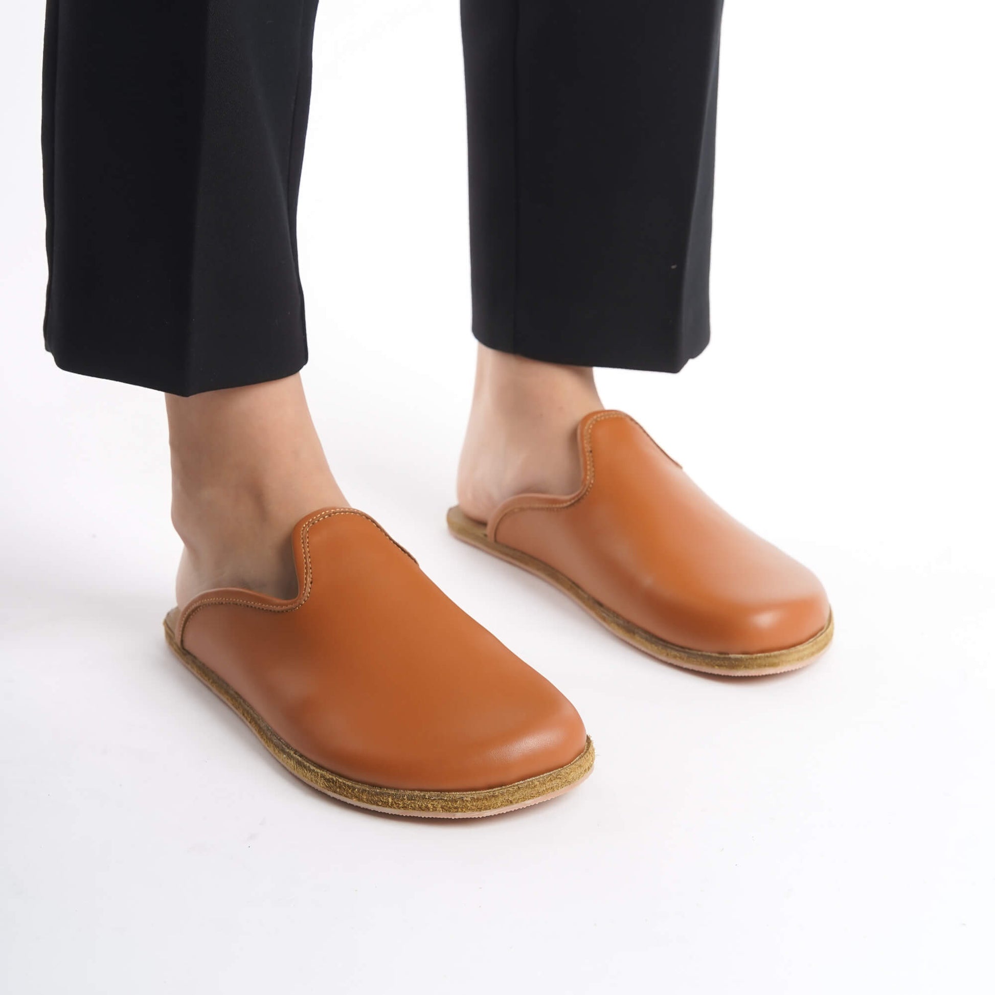 Chic tan leather slip-on shoes featuring a cozy cork sole, perfect for women seeking timeless comfort. These sustainable shoes offer flexibility and elegance, appealing to U.S. shoppers.