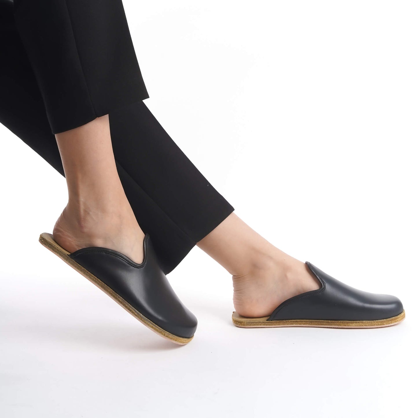 Timeless black leather slip-on shoes with a supportive cork sole, designed for women seeking versatile style. These lightweight, sustainable shoes are a staple for any U.S. wardrobe.