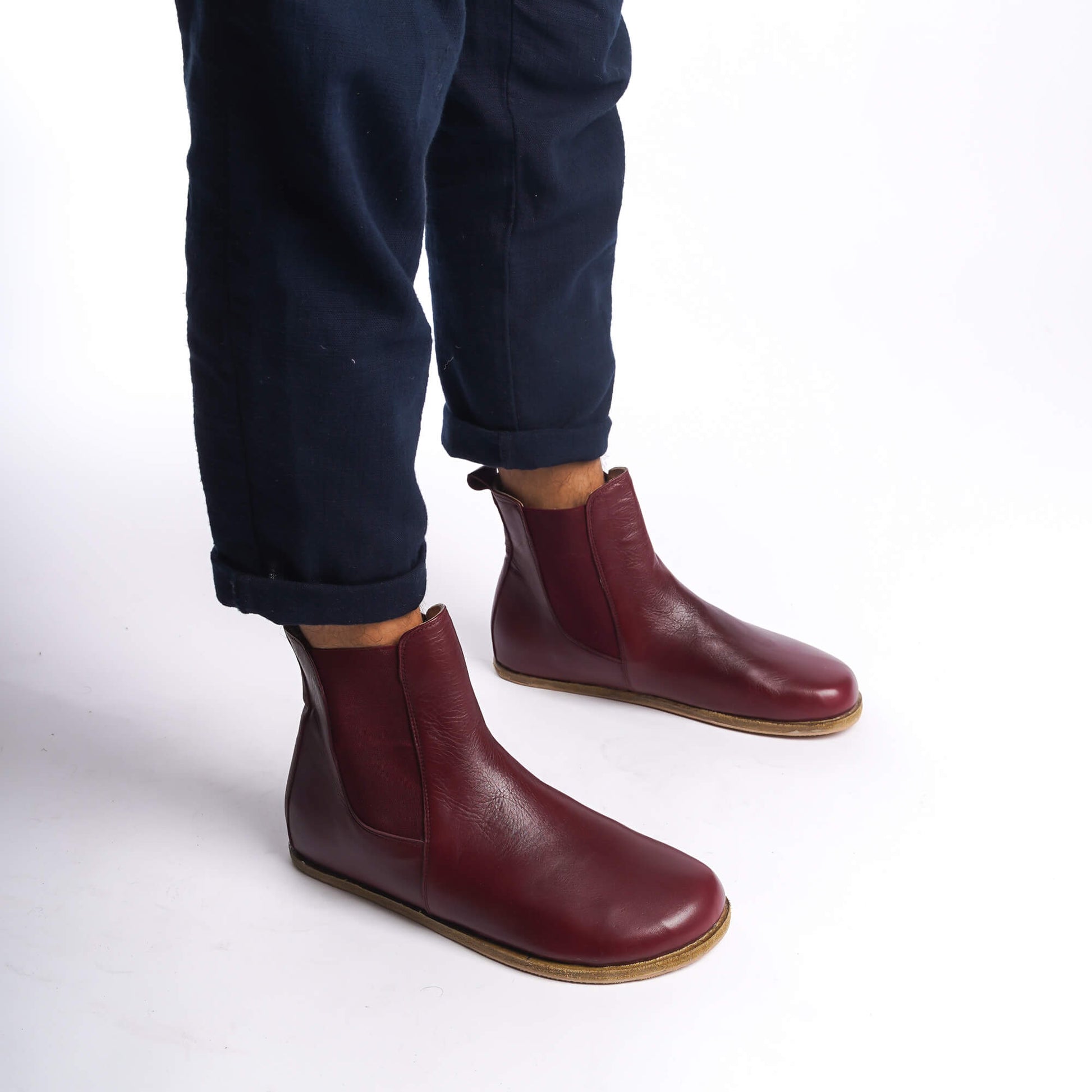 Side view of men's burgundy Chelsea boots, showcasing the minimalist design and rich leather material.Burgundy leather Chelsea boots for men, perfect for adding a touch of elegance to any outfit, with a slip-on design.