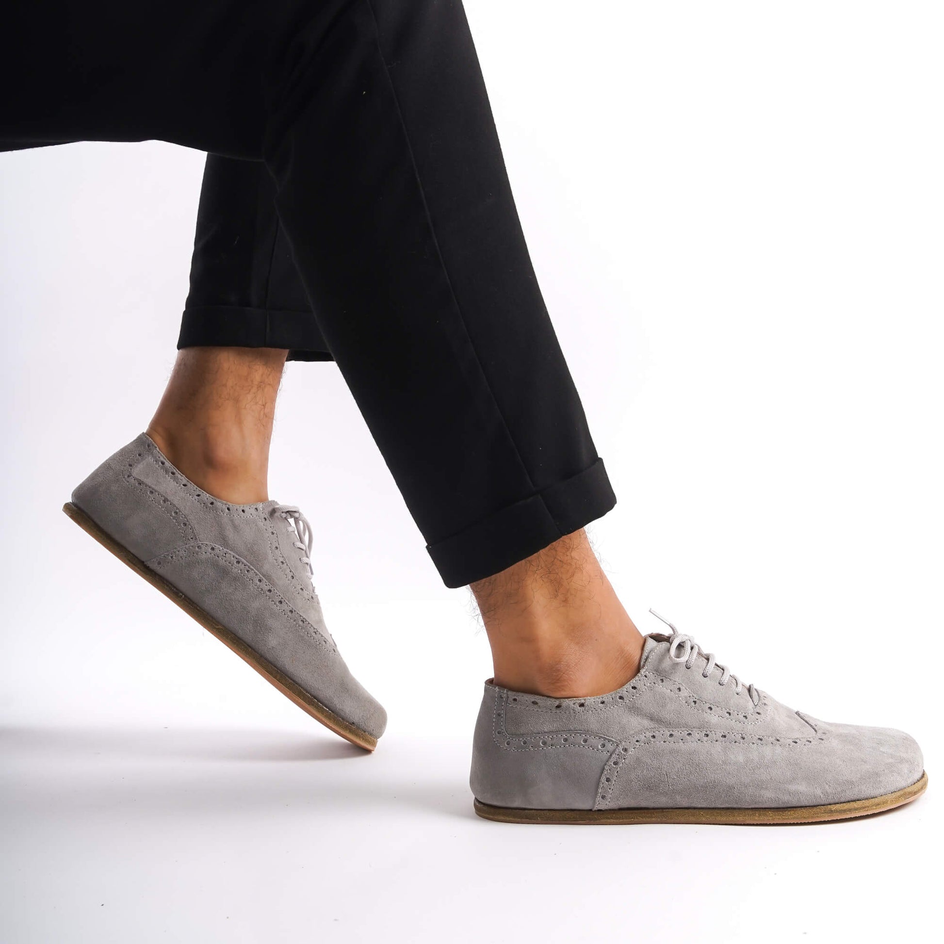 Close-up of gray suede barefoot Oxfords showcasing brogue details and natural foot shape.