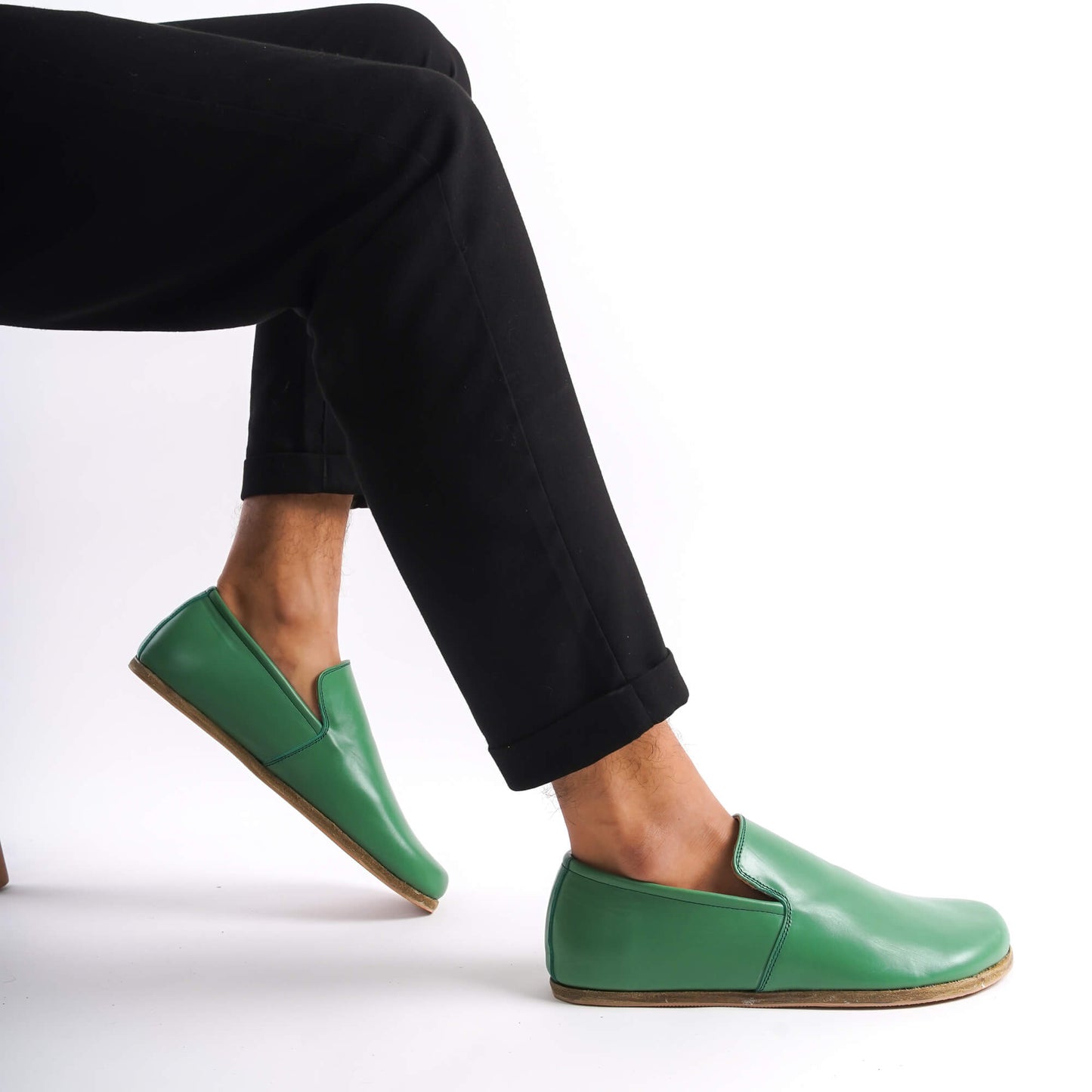 Green Aeolia Leather Barefoot Men's Loafers shown on feet with black pants, highlighting the sleek and versatile design.