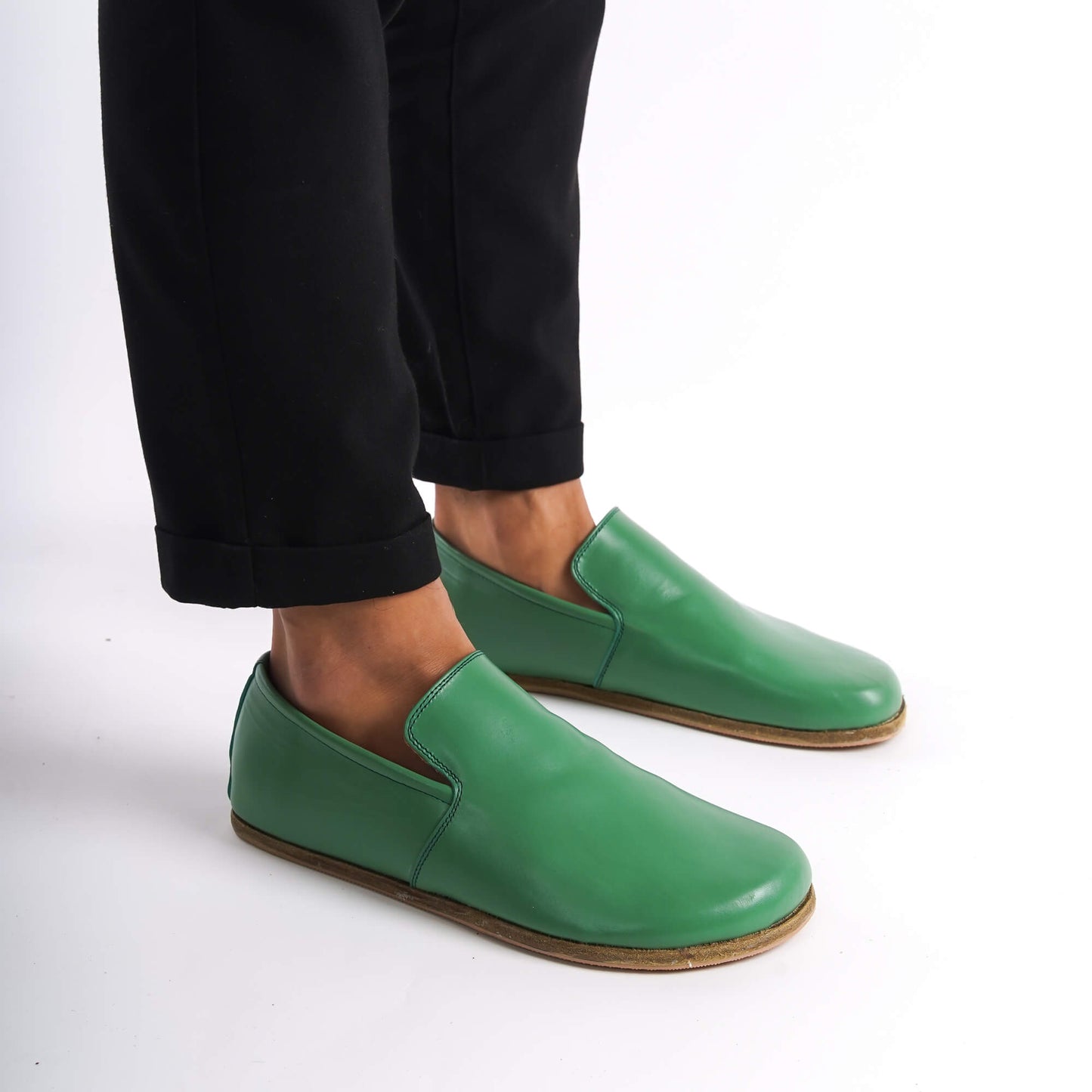 Green Aeolia Leather Barefoot Men's Loafers shown on feet with black pants, highlighting the minimalist design and wide toe box.