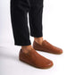 Tan brown Aeolia Leather Barefoot Men's Loafers shown on feet with black pants, highlighting the sleek design and comfort.