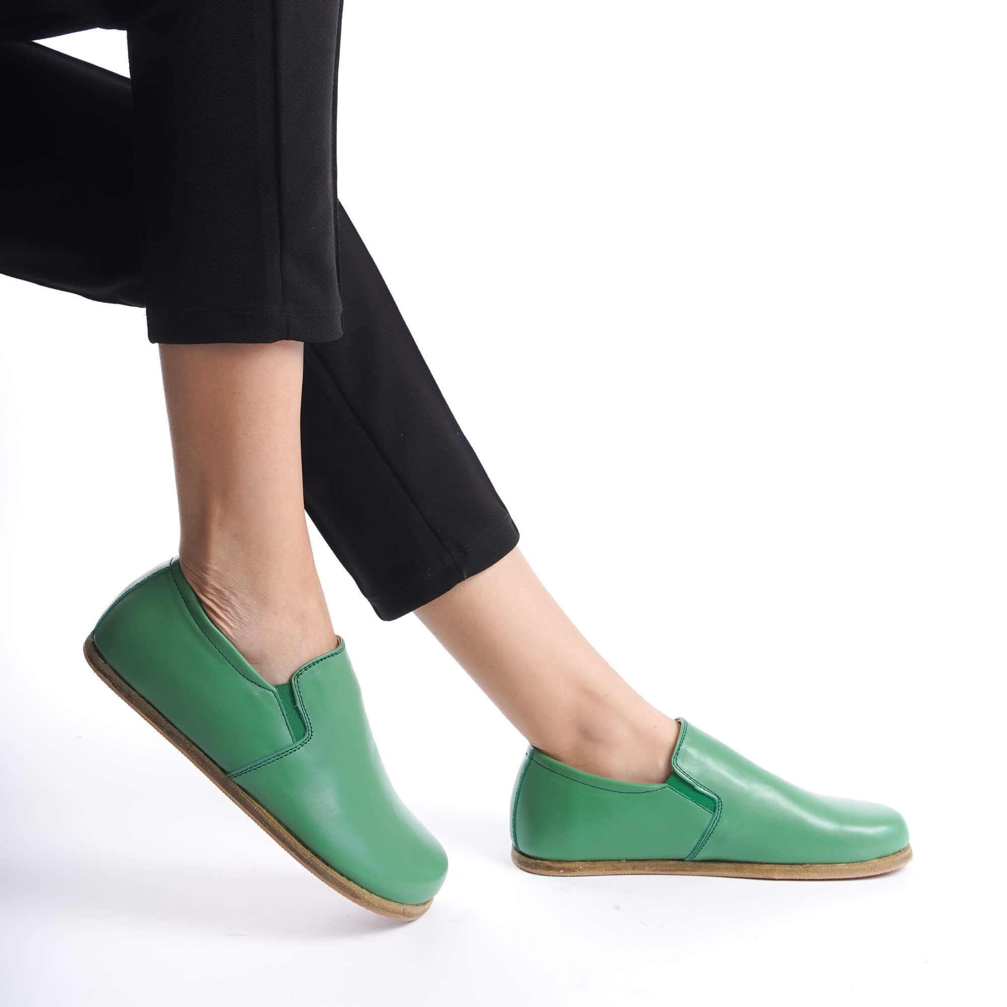 Close-up of feet in green leather barefoot loafers. Pelanir's zero-drop shoes for enhanced foot health.