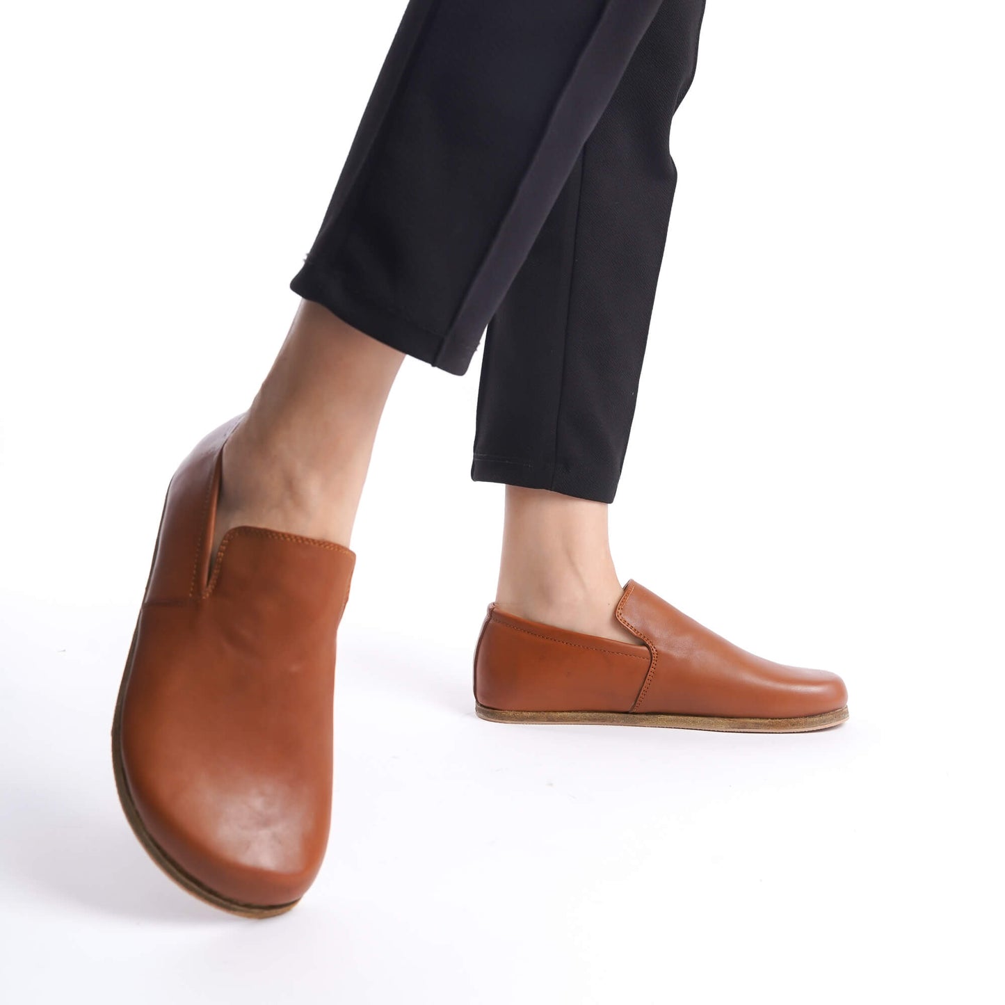 Aeolia tan brown leather barefoot women loafers, paired with black pants, featuring a minimalist and comfortable design.