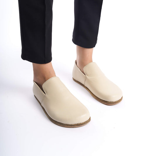 Woman wearing Aeolia Beige Loafers with black pants, showcasing the shoe's minimalist design and comfortable fit.