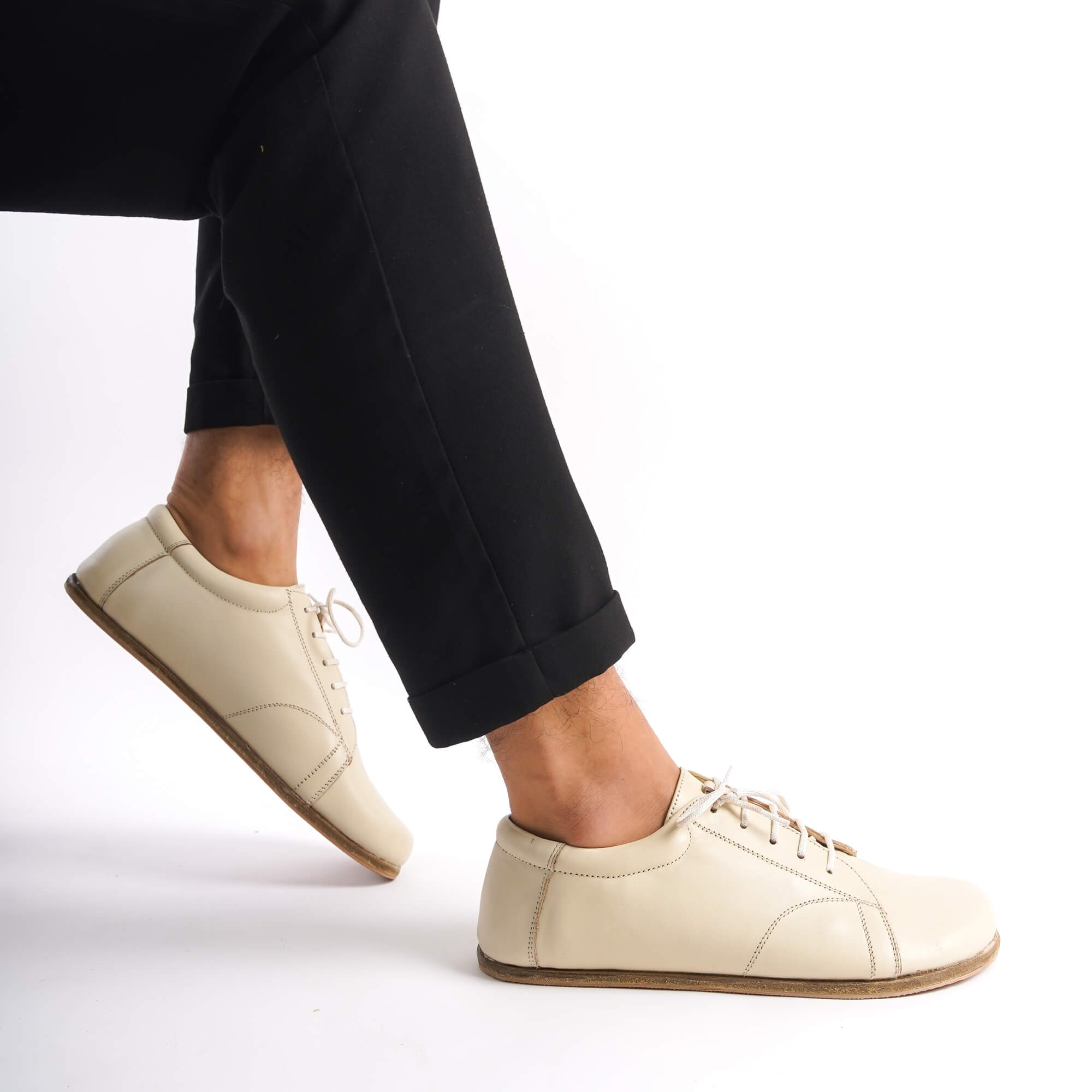 Side view of Lydia Leather Barefoot Men's Sneakers in beige, demonstrating the flexible and lightweight build for everyday wear.