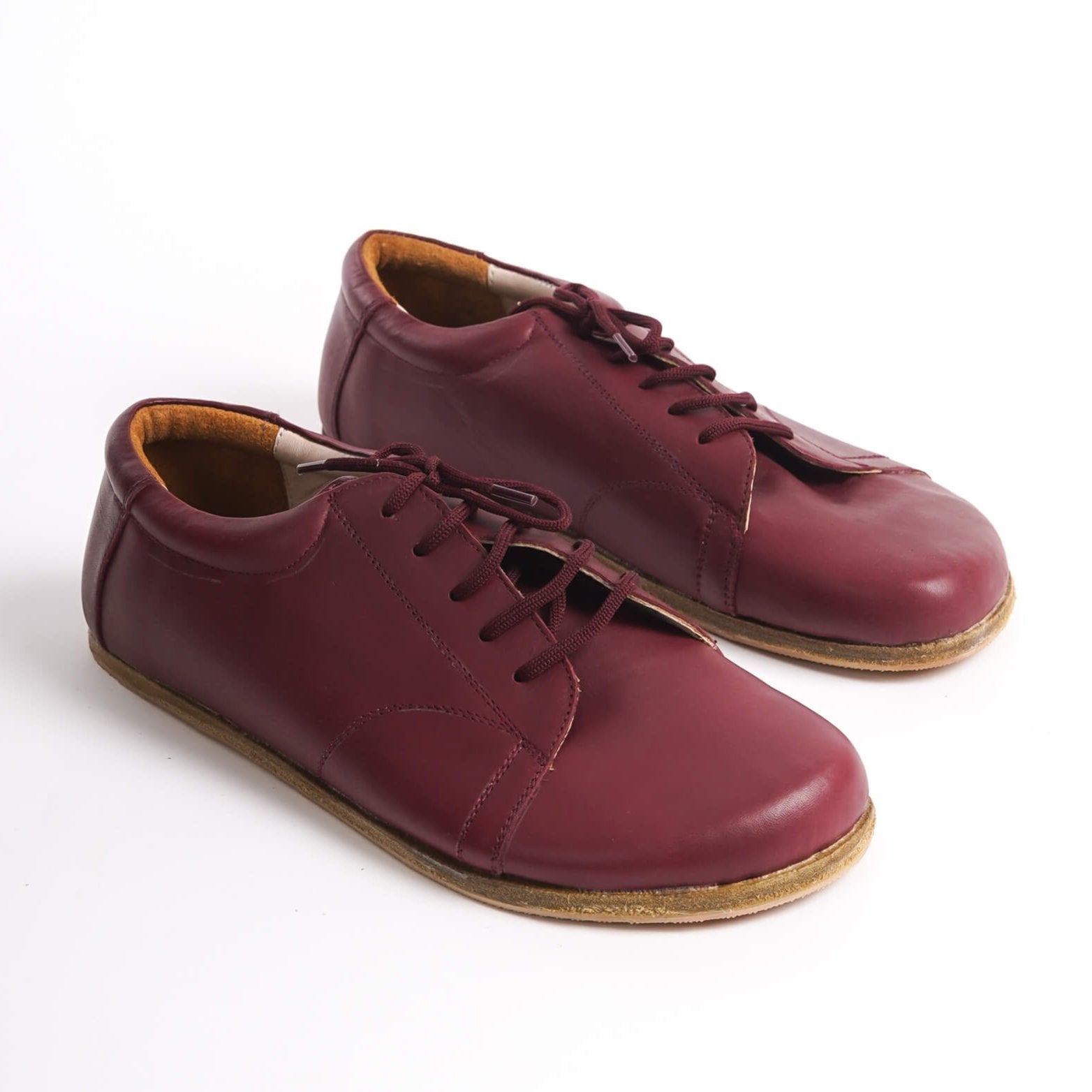 Pair of burgundy Lydia Leather Barefoot Men's Sneakers showcasing the rich color and natural leather material.