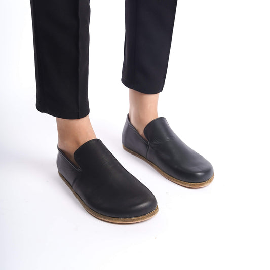 Model Wearing Aeolia Leather Barefoot Women Loafers in Black - Mid-Walk Showing the Shoe's Flexibility and Comfort.