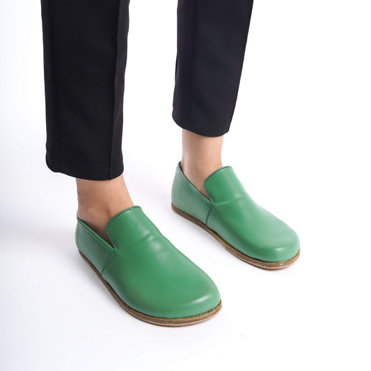 Close-up of Aeolia green leather barefoot women loafers, paired with black pants.