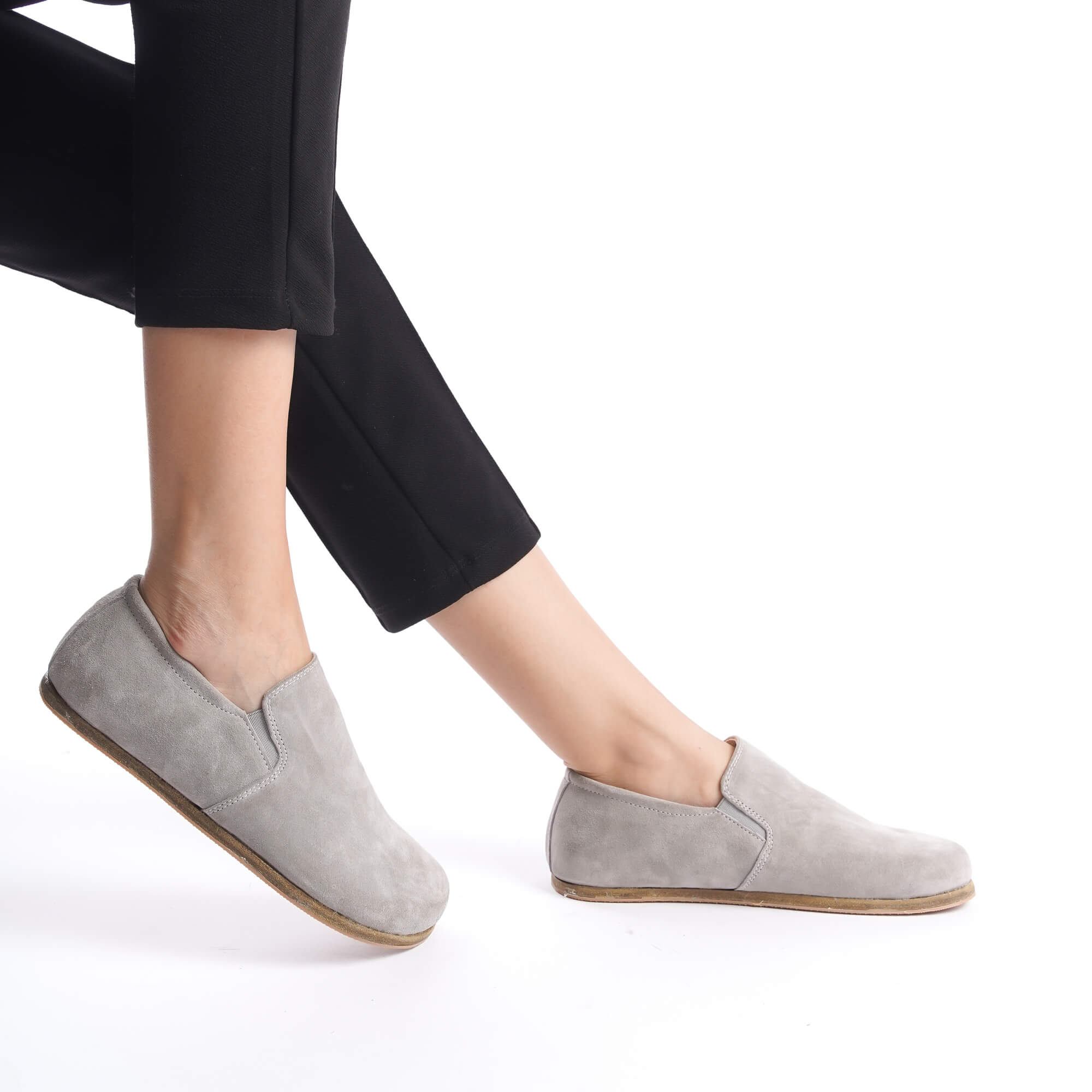 Gray suede barefoot loafers with black pants, featuring a comfortable and natural barefoot design.