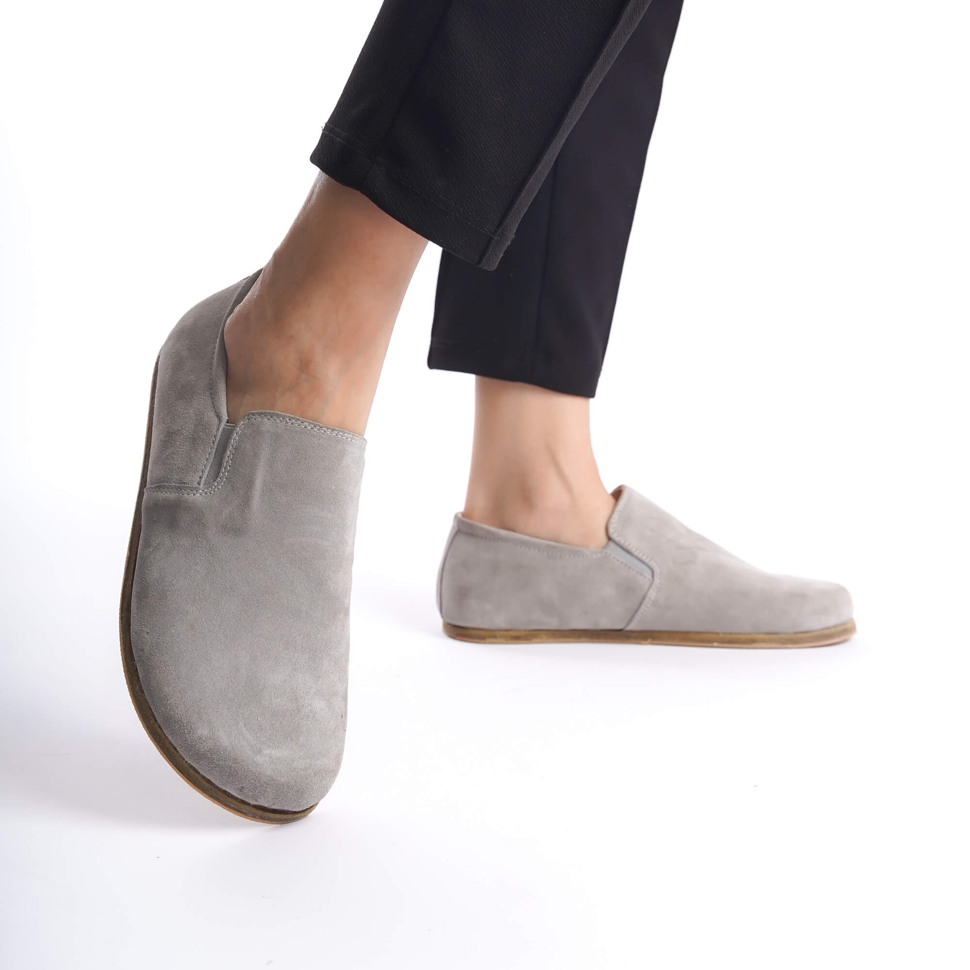 Minimalist gray suede loafers worn with black pants, highlighting their sleek and natural fit design