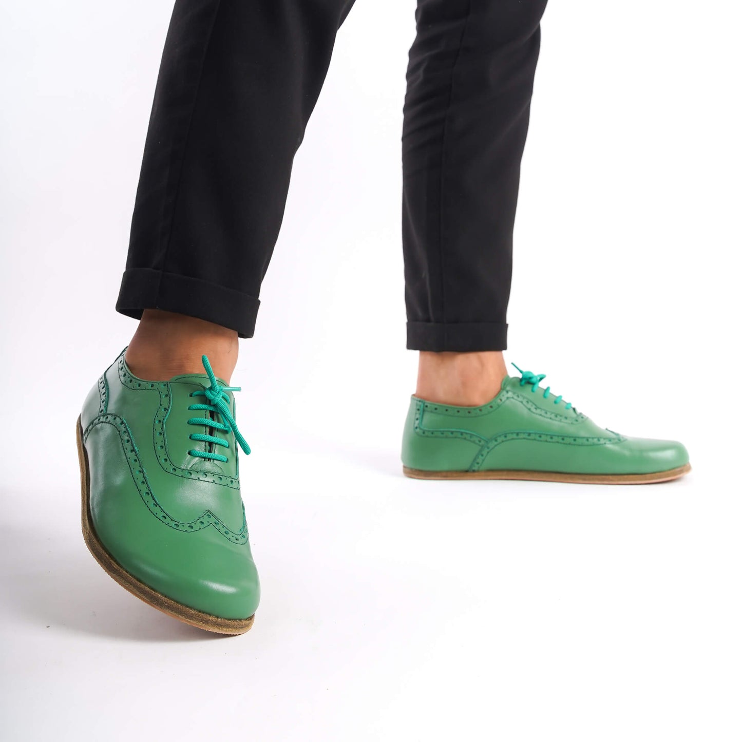 Man walking in green Doris Leather Barefoot Oxfords with brogue design, highlighting foot flexibility.