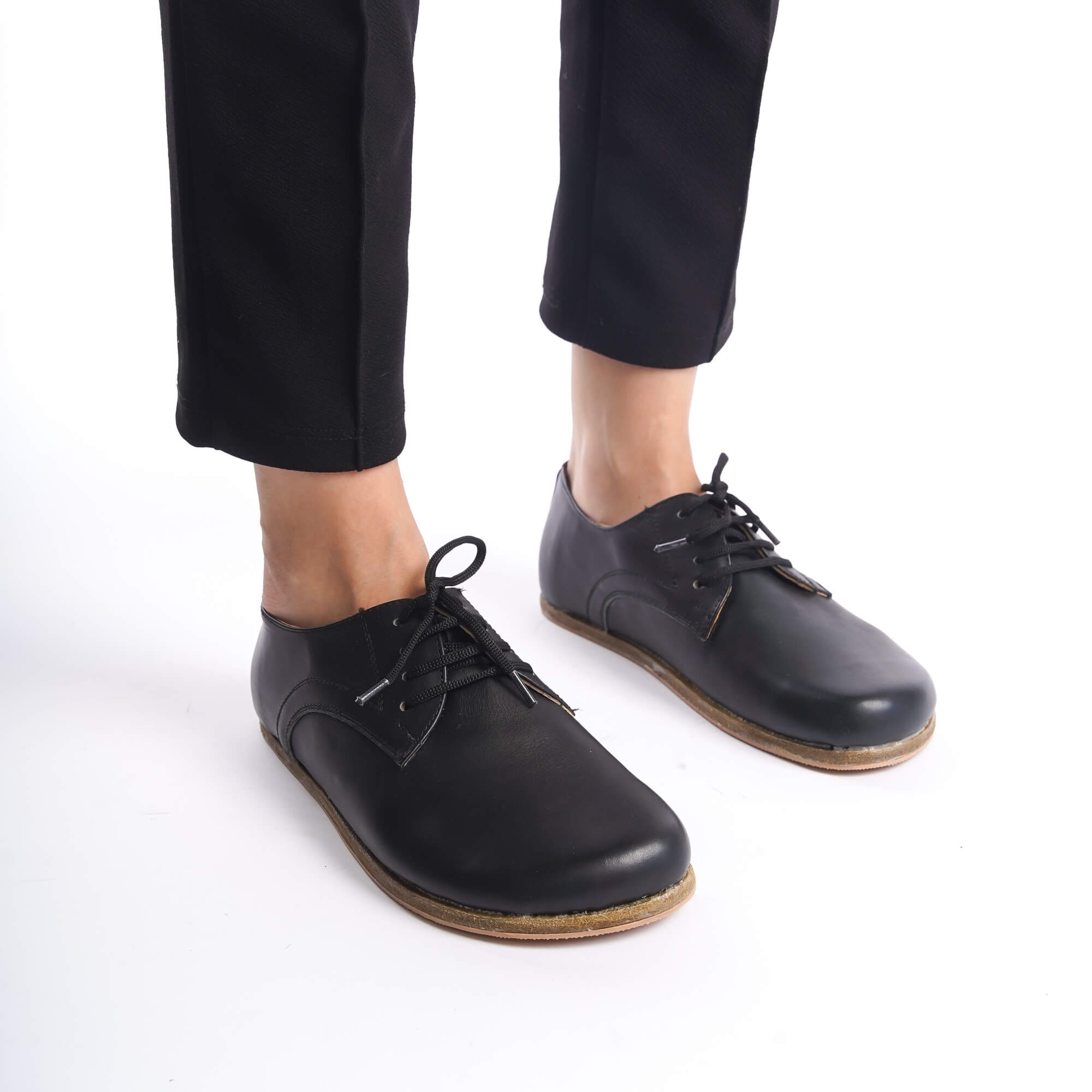 Close-up of black Locris Leather Barefoot Women Oxfords worn with black pants, showcasing the minimalist design and fine leather craftsmanship.
