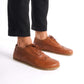 Man posing in tan brown Doris Leather Barefoot Oxfords, emphasizing their classic brogue design and fit.