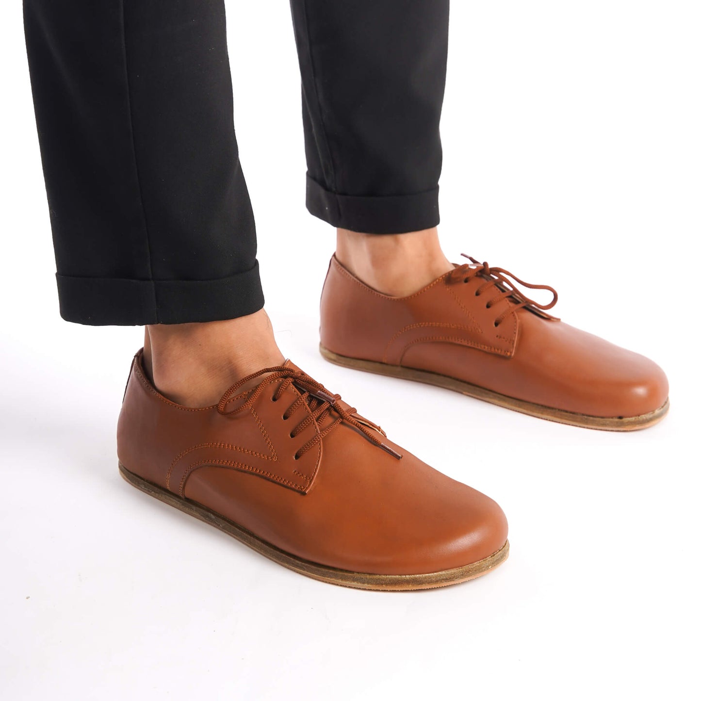Model wearing Locris Leather Barefoot Men's Oxfords in tan brown, demonstrating their lightweight and flexible construction.