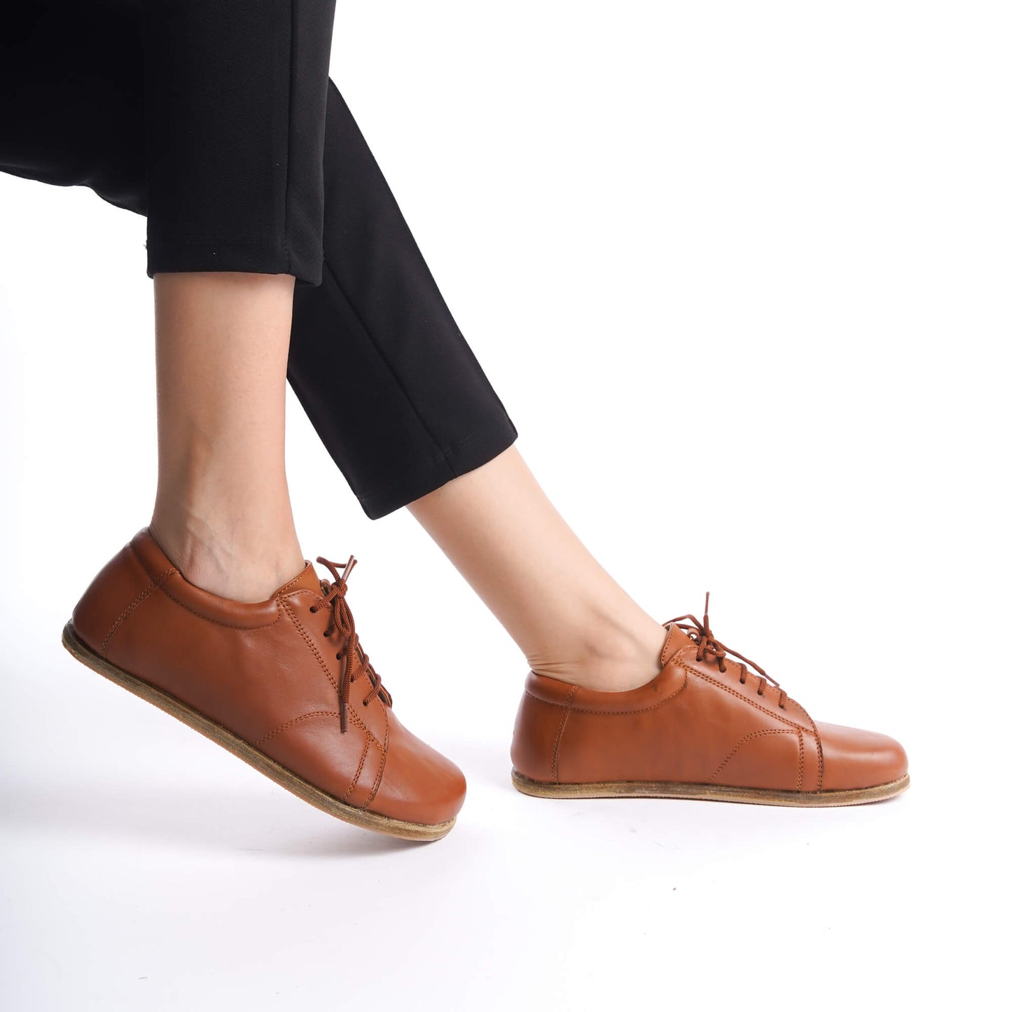 Model wearing Lydia Leather Barefoot Women's Sneakers in Tan Brown, perfect for a chic and comfortable look.