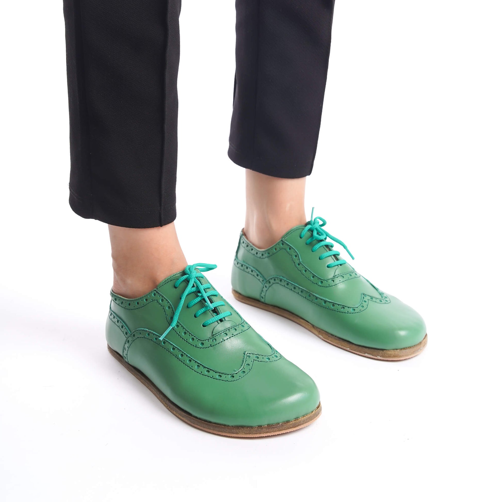 Close-up of green Doris Leather Barefoot Women Oxfords with teal laces, showcasing the brogue details.