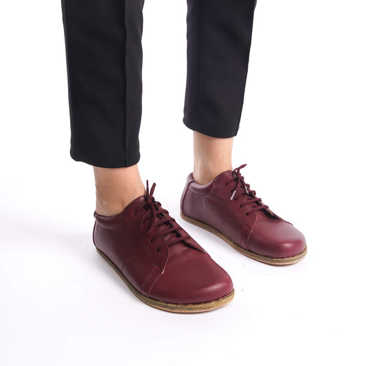 Close-up of Lydia Burgundy Leather Barefoot Women's Sneakers being worn, highlighting the sleek design and natural fit.