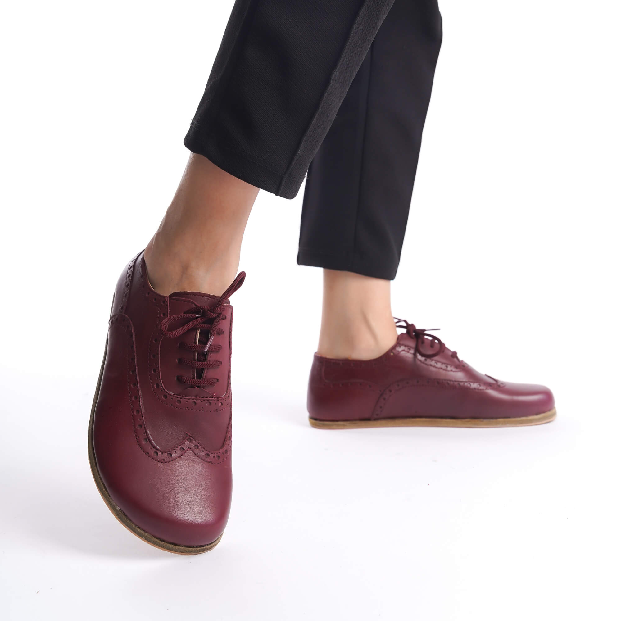 Side view of Burgundy Doris Leather Barefoot Women Oxfords worn with black pants for a stylish look.