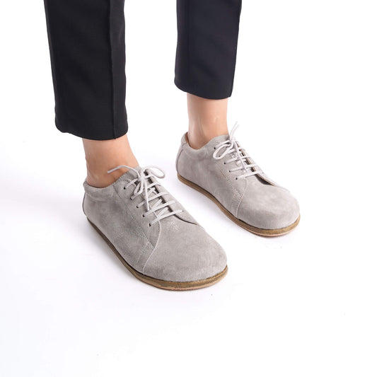 Gray suede barefoot sneakers worn with black pants, perfect for a casual and comfortable everyday look.