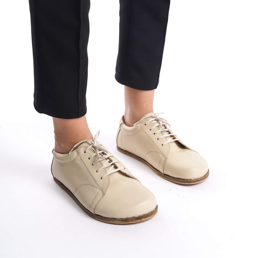 Detailed close-up of beige leather barefoot women's sneakers, highlighting the premium leather and precise craftsmanship.