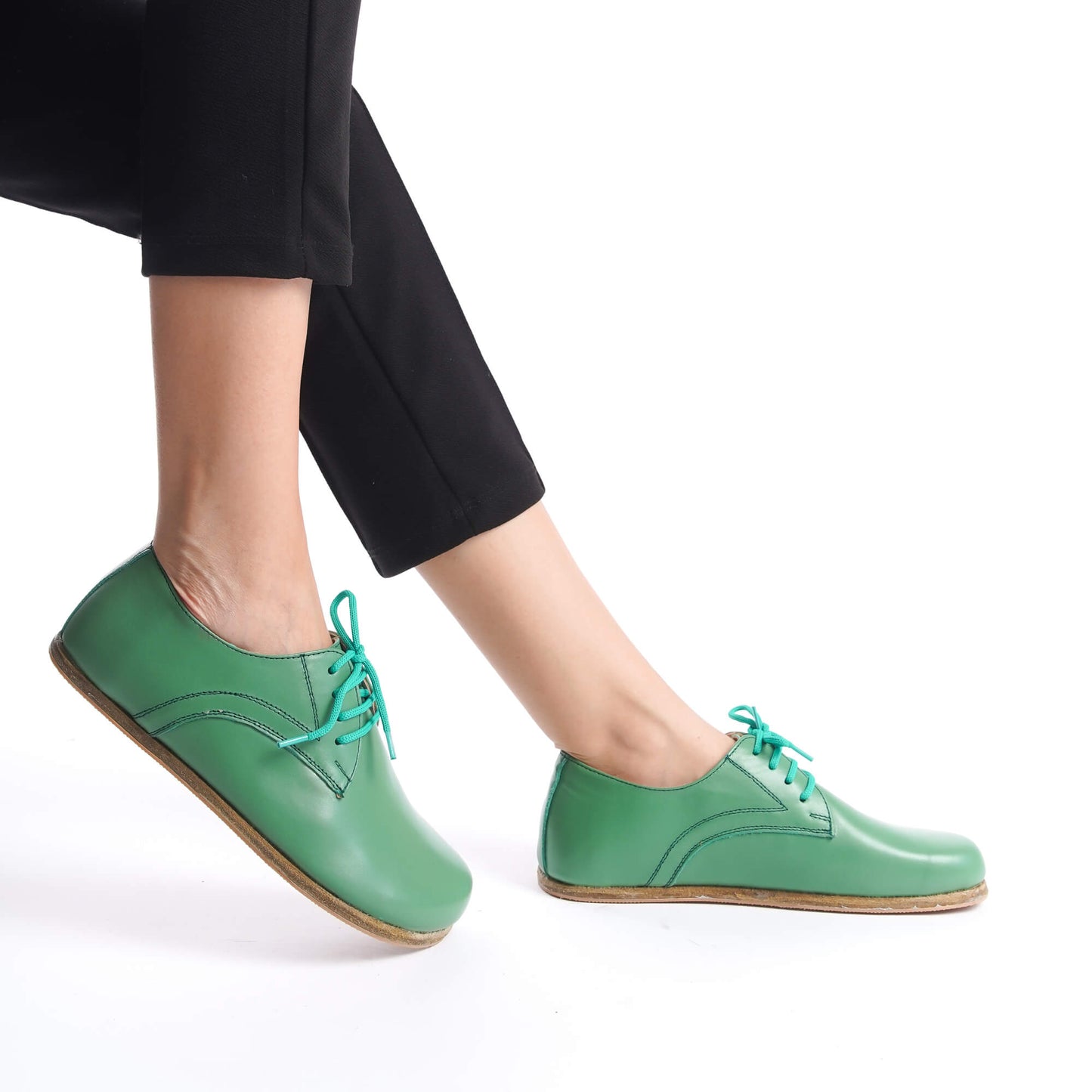 Side view of green Locris Leather Barefoot Women Oxfords worn with black pants, illustrating the wide toe box and zero-drop design for natural foot alignment.