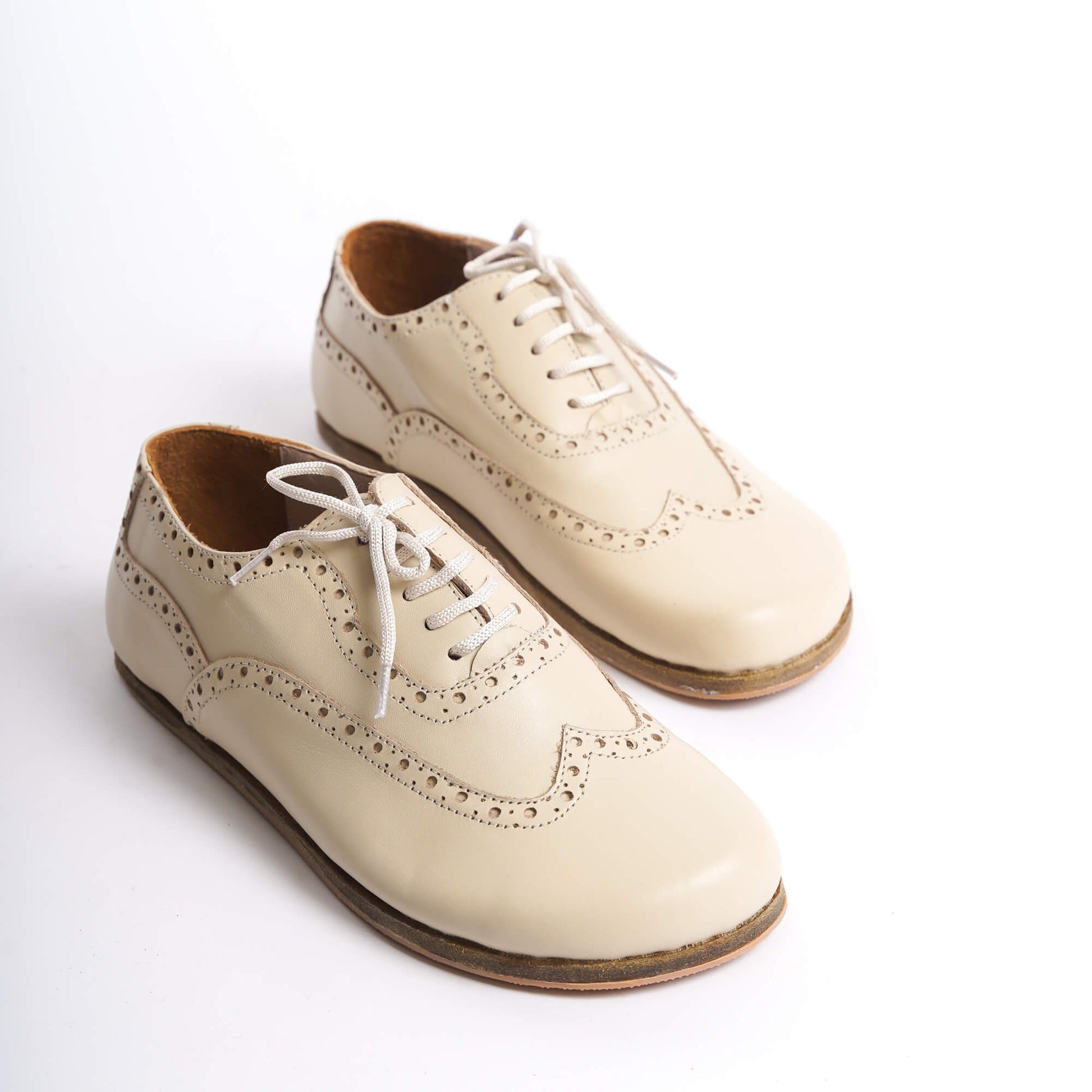 Close-up view of Doris Leather Barefoot Women's Oxfords in beige on a white background, showcasing intricate brogue detailing.