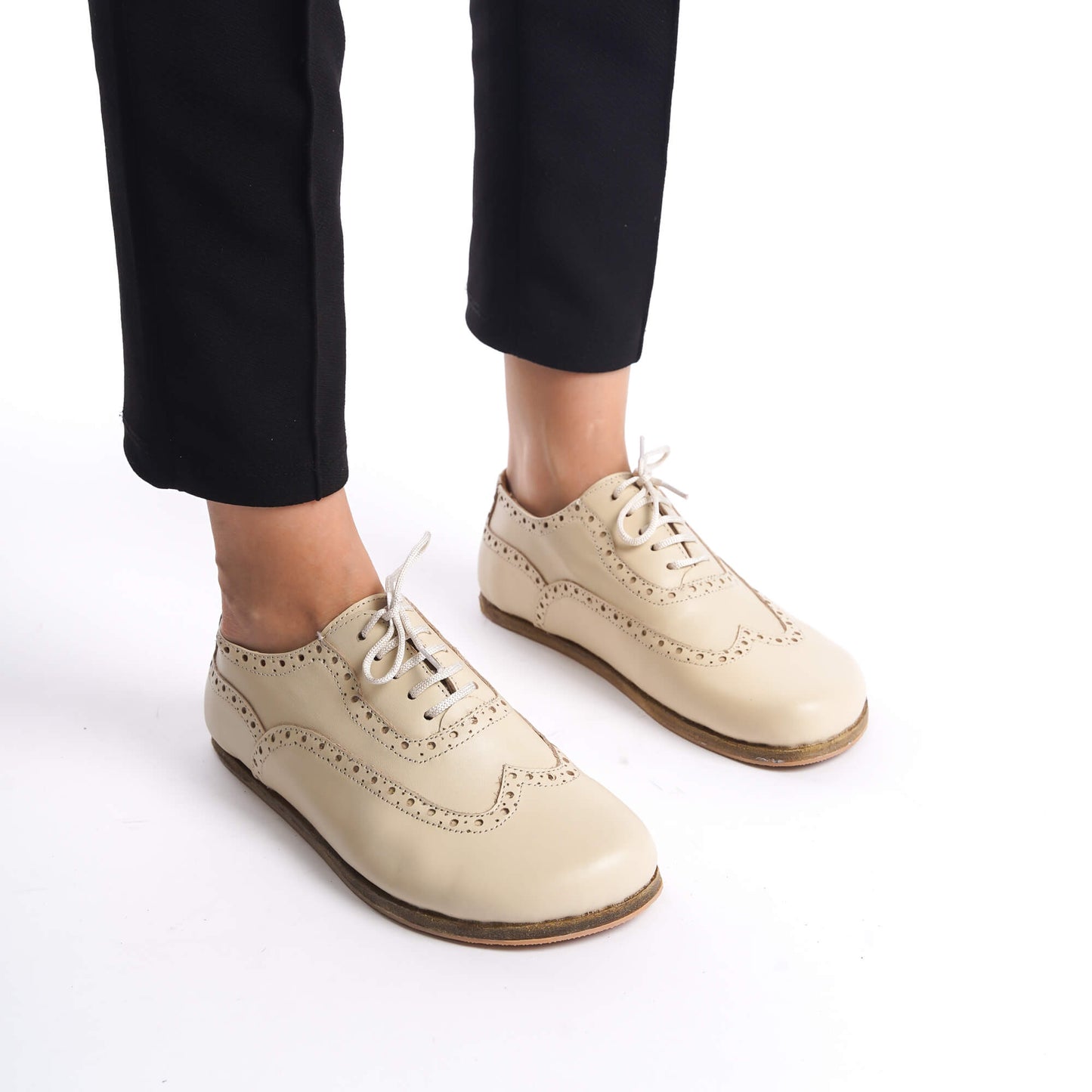 Woman's feet in beige Doris leather barefoot women's oxfords, highlighting their flexible sole and comfortable fit.