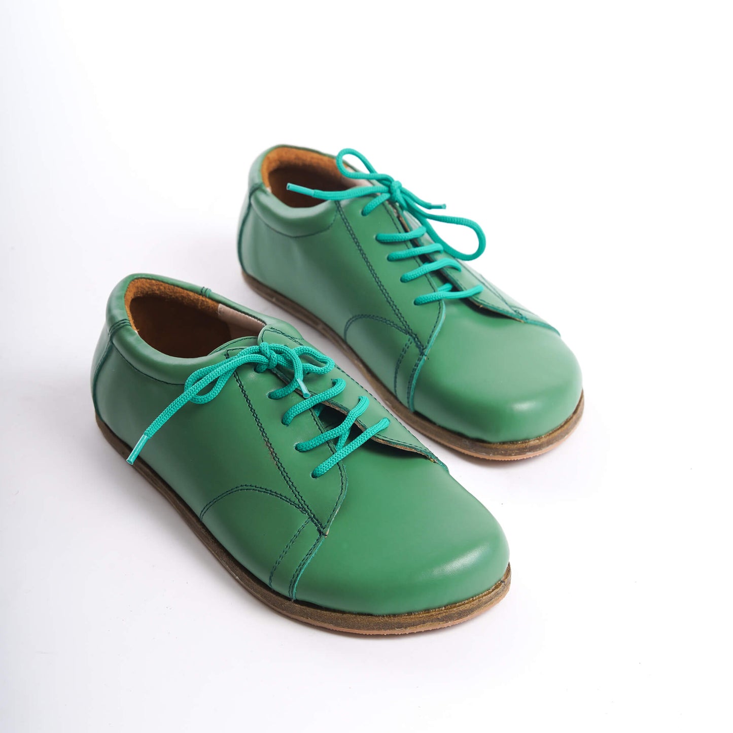 Pair of Lydia Leather Barefoot Women Sneakers in green with turquoise laces, showcasing a stylish and natural design.