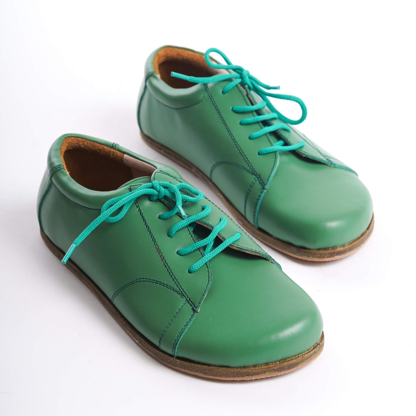 Pair of Lydia Leather Barefoot Women Sneakers in green with turquoise laces, showcasing a stylish and natural design.