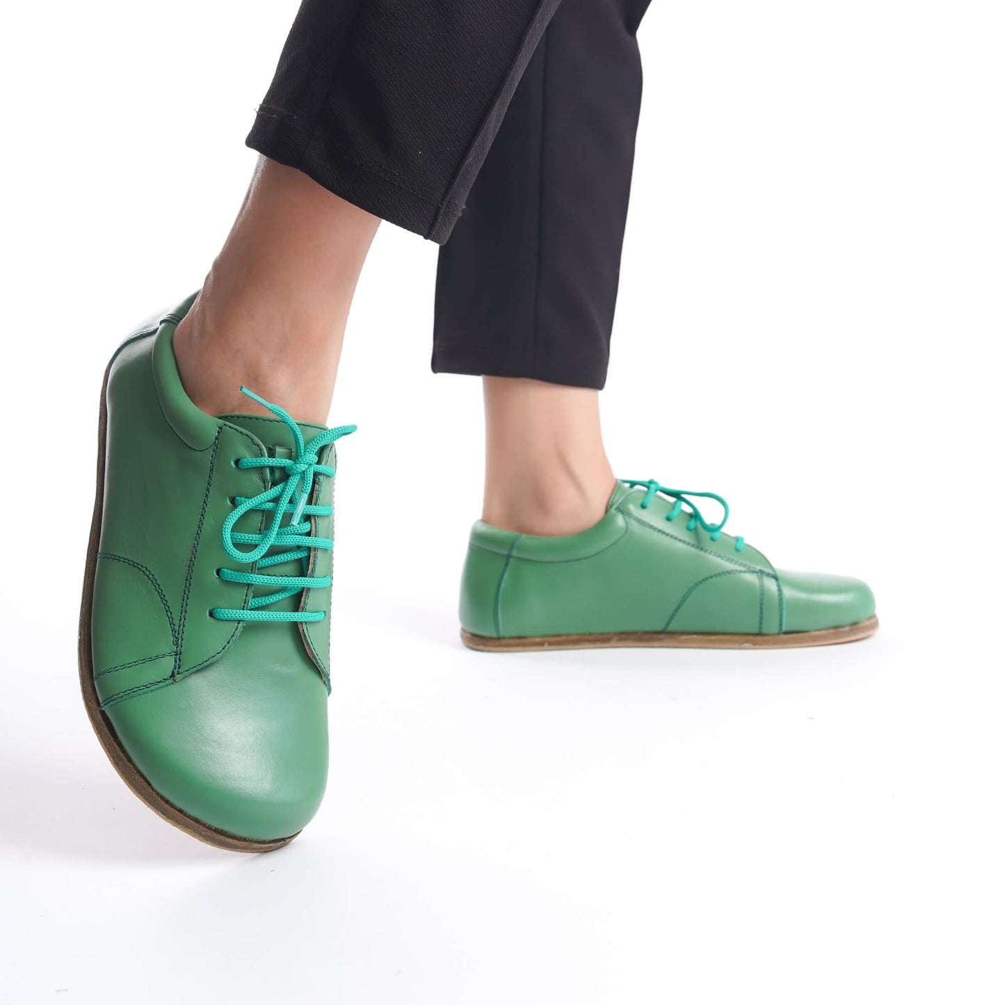 Close-up of green Lydia leather barefoot women's sneakers with turquoise laces, highlighting their minimalist design and genuine leather material.